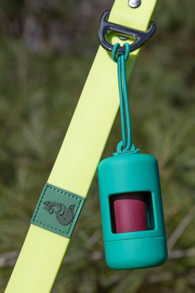 A green Fresh Peppermint Waste Bag Dispenser attached to a teal leash, designed to hold dog waste bags.