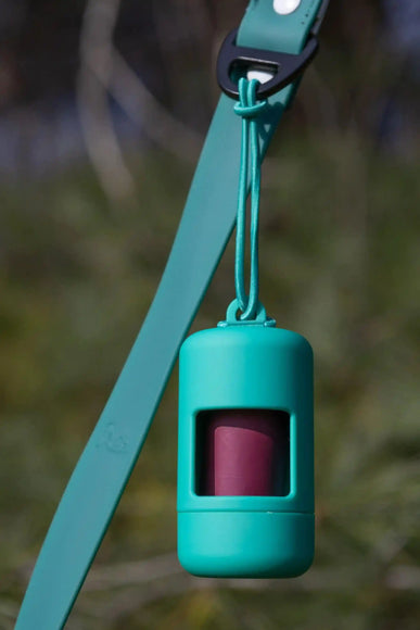 A green Fresh Peppermint Waste Bag Dispenser attached to a teal leash, designed to hold dog waste bags.